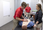 Athletic training majors Luke Lammert, left to right, Ryan Bussey, and Katie Plummer check the heartbeat on a SimMan Essential simulated patient during a demo in the new Athletic Training Simulation Lab at the Ramsey Center on Thursday afternoon. (Photo credit: Andrew Davis Tucker)