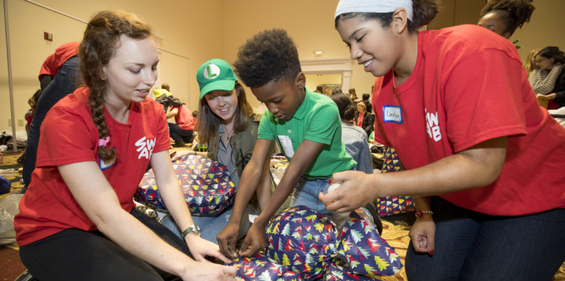 UGA students, from left, Brooke Johnson, Jillian Schmidt and Lindsey Shelton wrap gifts with Desmond Barnes, a student at Winterville Elementary School, during Shop with a Bulldawg. Schmidt is executive director of the student group.