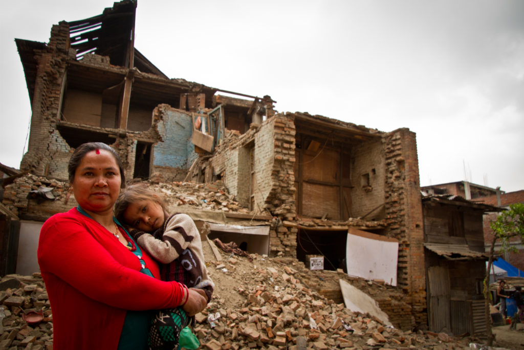Mother and child outside earthquake ruined home