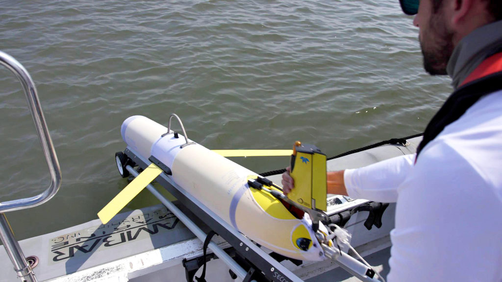 Photo of UGA Skidaway Institute research technician Ben Hefner launching a glider into the ocean. 