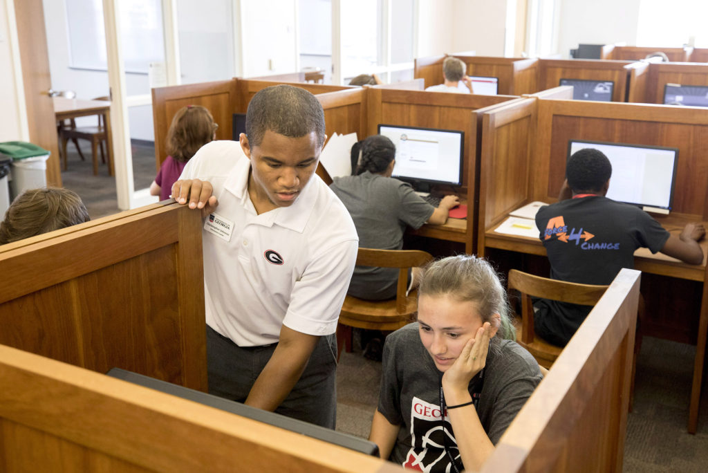 Photo of Christopher Johnson helping a female student in a computer lab.