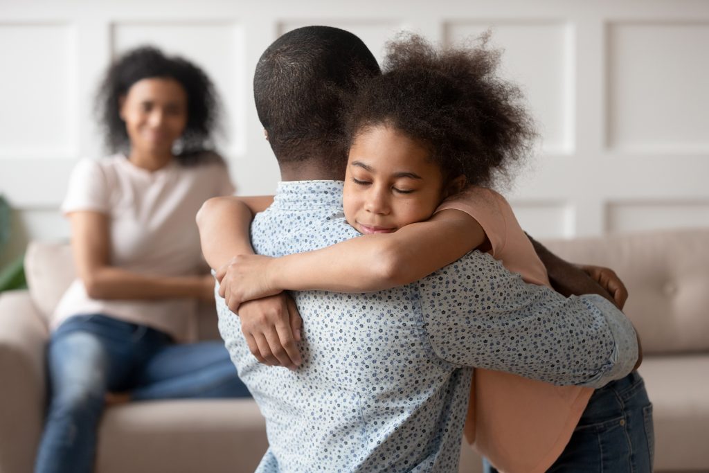 Little school girl embracing father.