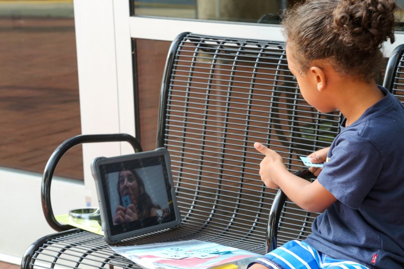 A child attending virtual school outside the Clarke County Public Library.