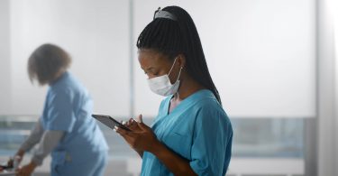 nurse wearing safety mask using digital tablet