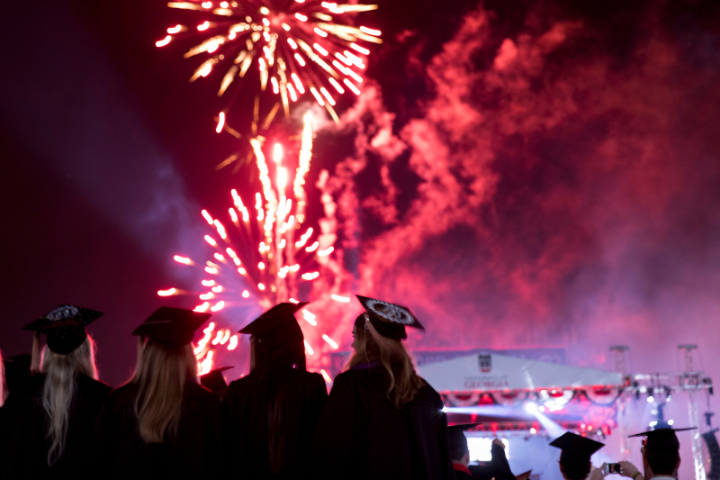 Image of 4 graduates watching fireworks at the UGA Commencement.