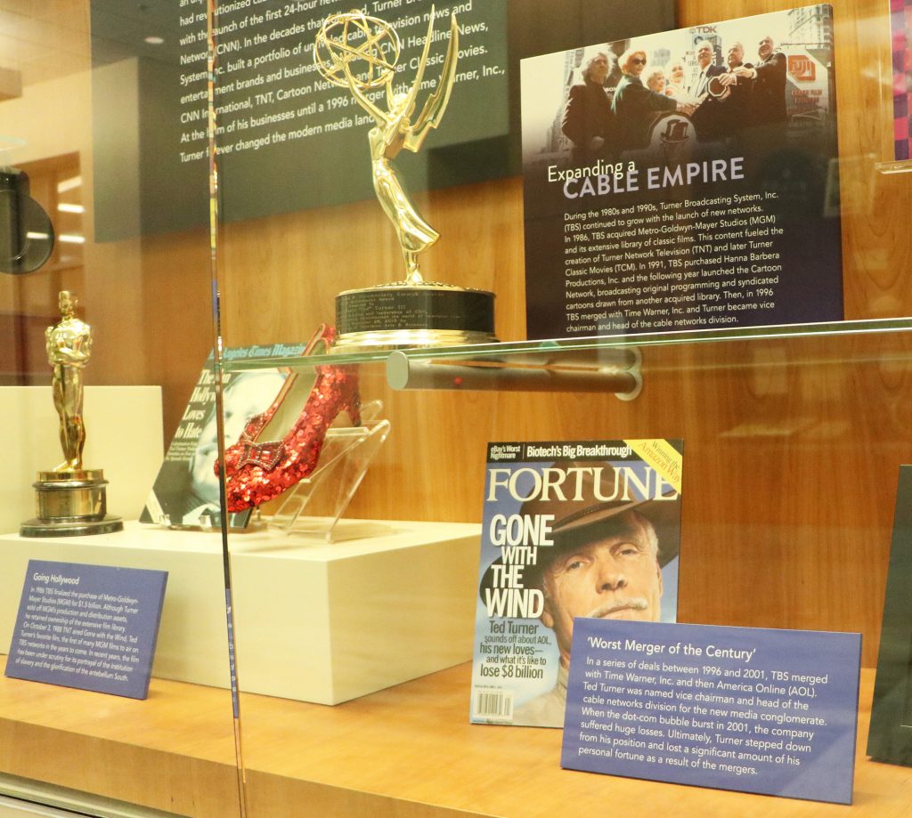 A glass display case with trophies and magazine covers.