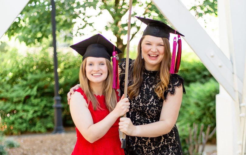 Amelia and Megan Holley wear graduation mortarboards and ring the UGA Chapel Bell.