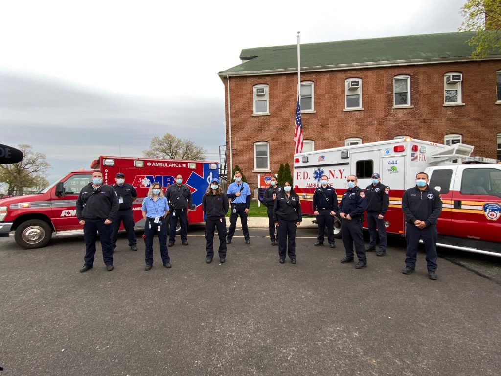 Emergency workers posing in front of ambulances.