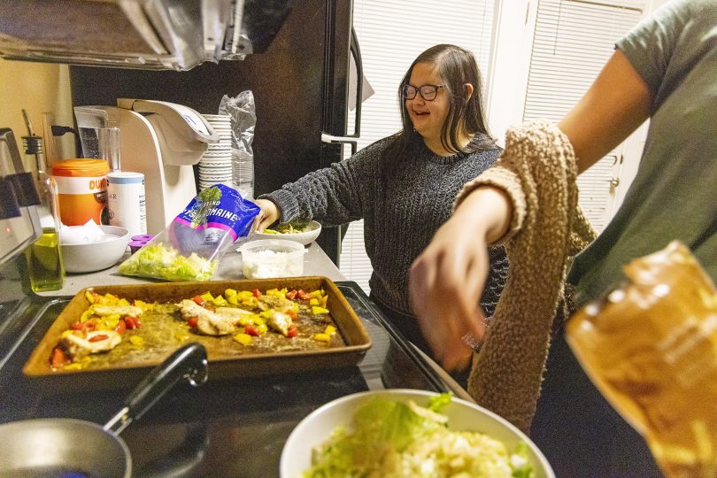 Marina Martinez adds some lettuce to her plate as she makes dinner with her roommates.