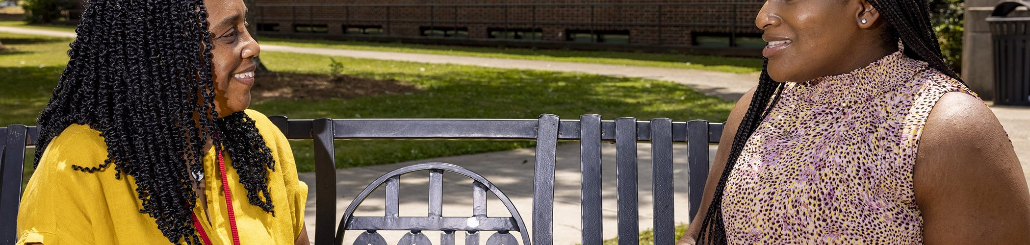 student and counselor sitting on bench outside high school