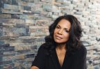 Audra McDonald poses in front of a brick wall.