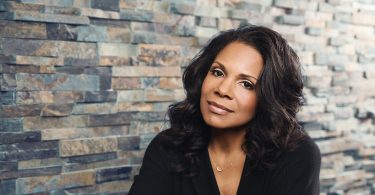 Audra McDonald poses in front of a brick wall.
