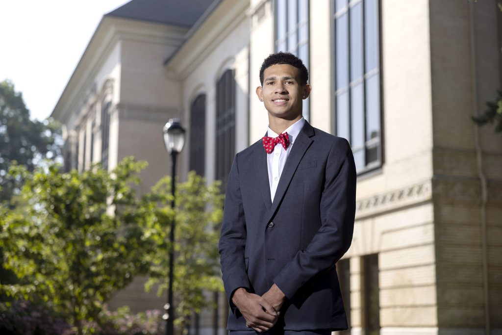 Jay Ivey in a suit and red bow tie stands in front of a building.