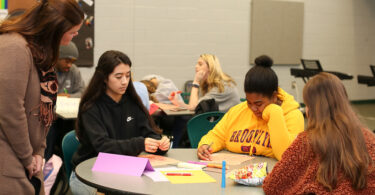 Three students sitting at a table working on a leadership project.