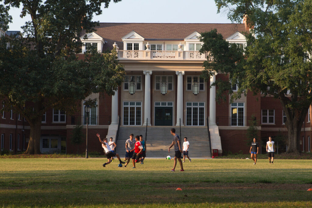 Students play soccer outside a campus residence hall.