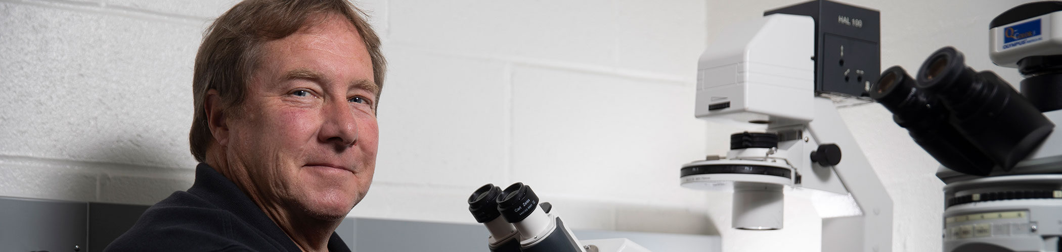 Researcher Ralph Tripp sits in front of a microscope