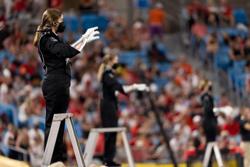 Drum majors direct the band as the Redcoat Marching Band performs on the field.