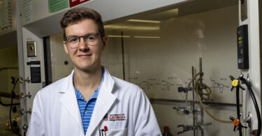 Portrait of student Ransom Jones wearing a lab coat in a lab.