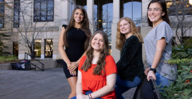 Four female college students in front of a university building