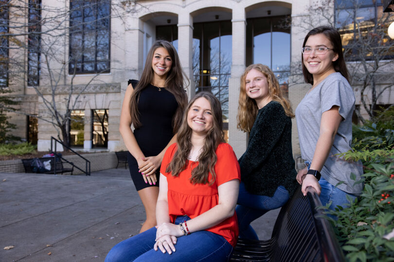 Four female college students in front of a university building