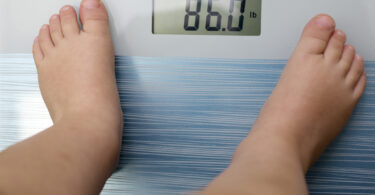 A child's feet are shown on an electronic scale that reads 86 pounds.