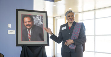 Marilyn Holmes stands beside portrait of her late husband, Hamilton Holmes Sr.