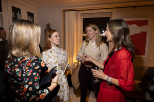 Clarke networks with guests at her alumni event hosted in her New York City apartment. She is seen talking with three other women. 
