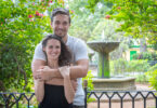 Jeremy and Lindsey pose together for a photo in a garden setting in front of a fountain.
