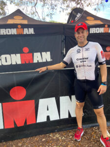 Crozier poses in front of an Iron man sign, dressed in his racing uniform. 