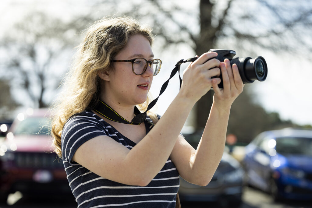 girl in blue shirt holding camera