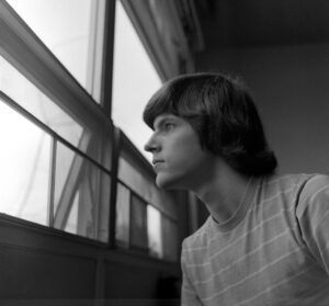 Black and white picture of Philip Bouchard looking out a dorm room window in the 1970s.