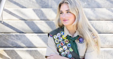 Catherine Hagerty poses in front of a building in her Eagle Scout uniform with the badges she earned.
