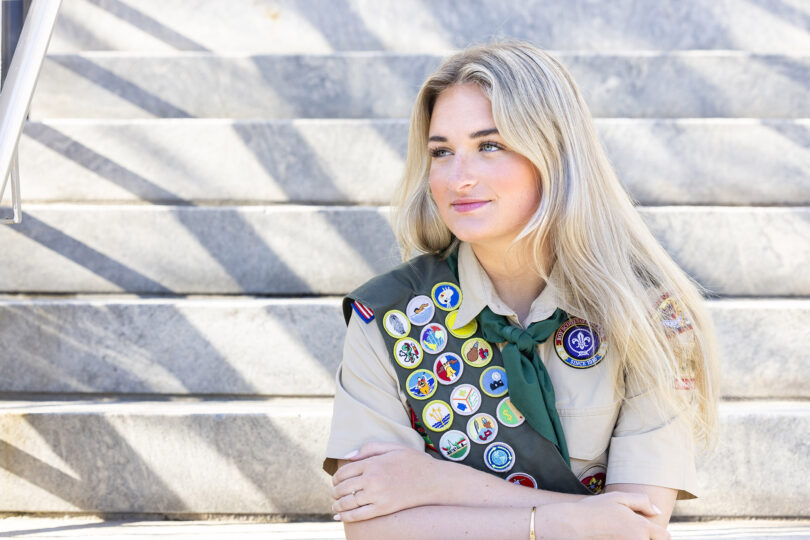 Catherine Hagerty poses in front of a building in her Eagle Scout uniform with the badges she earned.