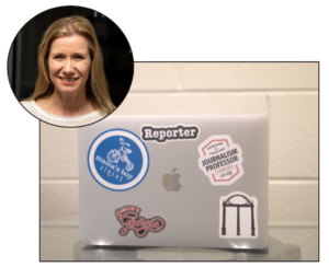 Professor Lori Johnston is pictured in a bubble in the corner of the image, with a photo of her laptop in the main frame. She has several stickers on the lid, including one depicting the UGA arch
