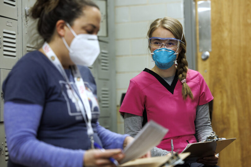 woman in pink scrubs and blue KN95 mask
