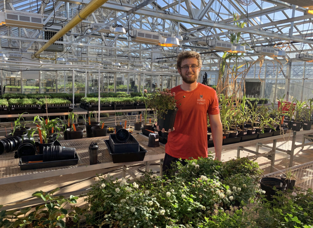 Vincent Pennetti holds a clover plant in a greenhouse.