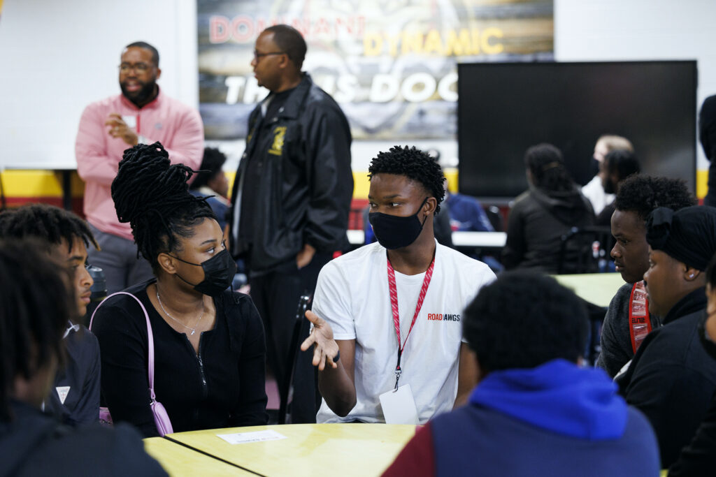 Black students in masks talking at a table
