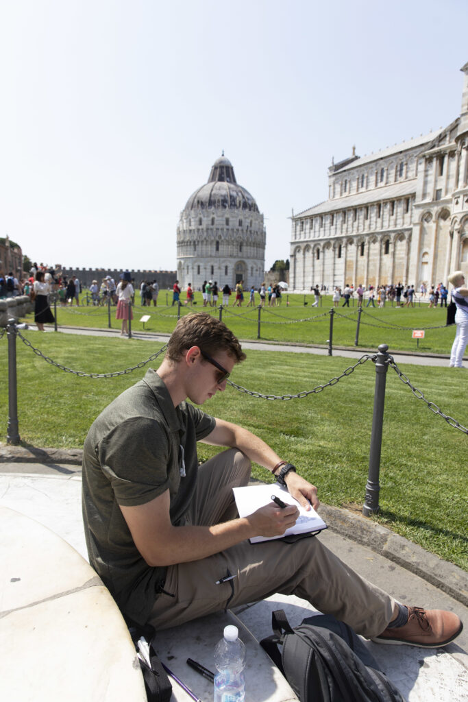 Student sketching with the Tower of Pisa in the background