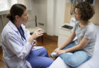 A female doctor sits down with a young female patient.