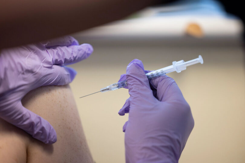 Close up shot of an arm being injected with a COVID-19 vaccine.