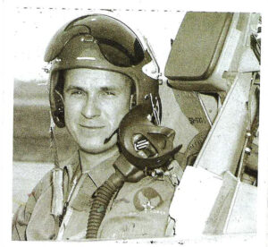 Black and white photo of a man in the cockpit of a figher jet.