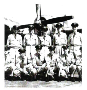 11 service Air Force airmen pose for a black and white photo in front of a bomber aircraft.
