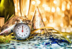 A New Year's party hat and clock are shown on a table