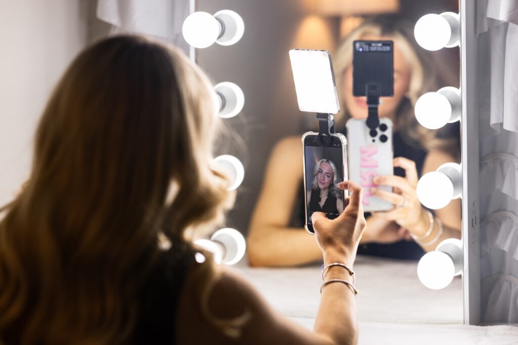 Jillian Rhae Maxwell poses for a selfie in front of a lighted mirror.