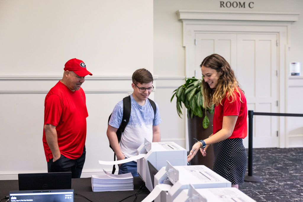 UGA orientation leader Blake Witmer shows a potential student and their parent a printer during a tour of the University of Georgia.