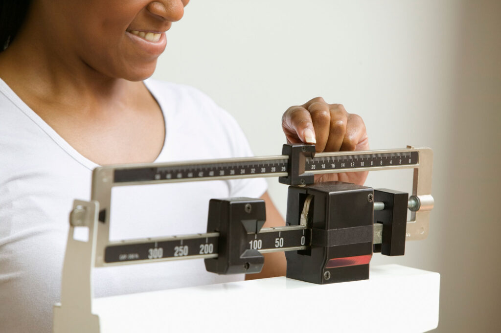 A woman is shown using a scale like those used in doctor offices.