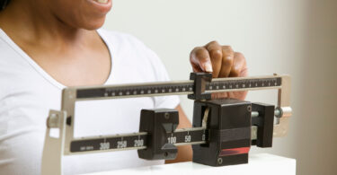 A woman is shown using a scale like those used in doctor offices.
