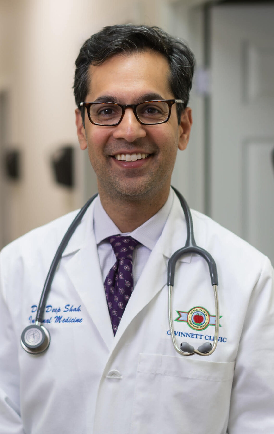 Portrait of UGA Rhodes scholar, Deep Shah, in a white doctor's coat, smiling