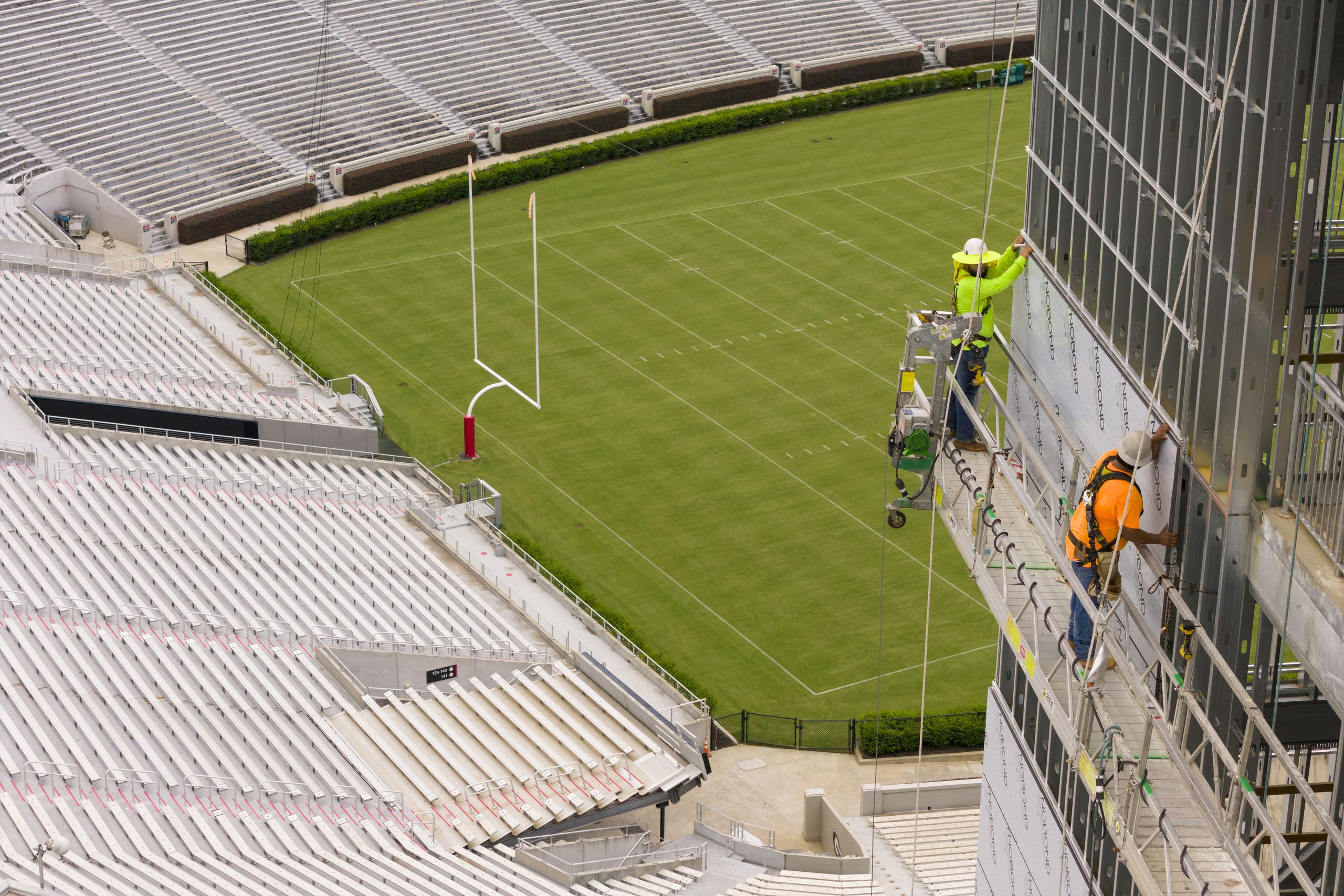 Construction workers apply the exterior covering to the stairwell outside the new press box on the southwest corner of Sanford Stadium.