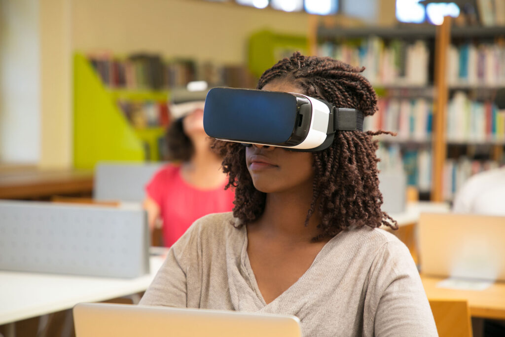 A young girl wears a virtual reality headset in a classroom.